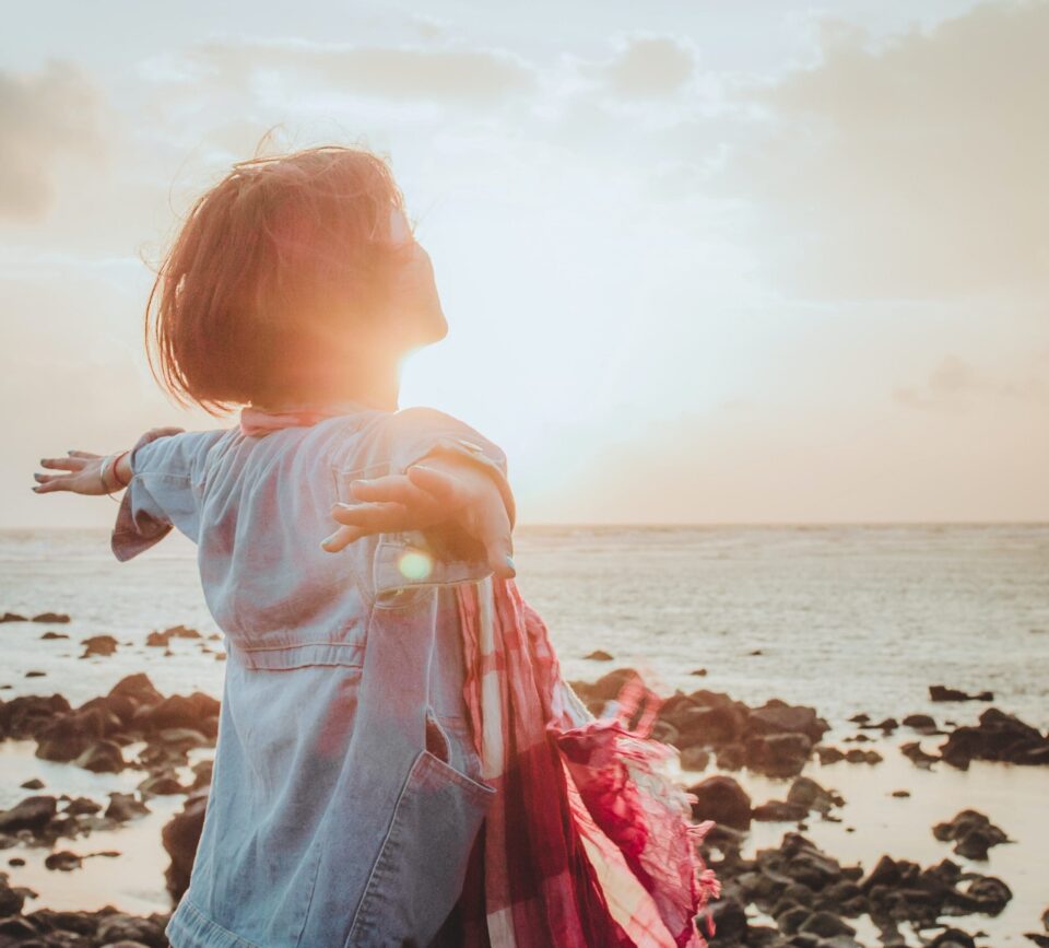 A woman standing on the beach with her arms outstretched. A woman standing on the beach with her arms outstretched.