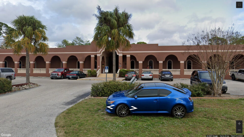 A blue car parked in front of a building. A blue car parked in front of a building.