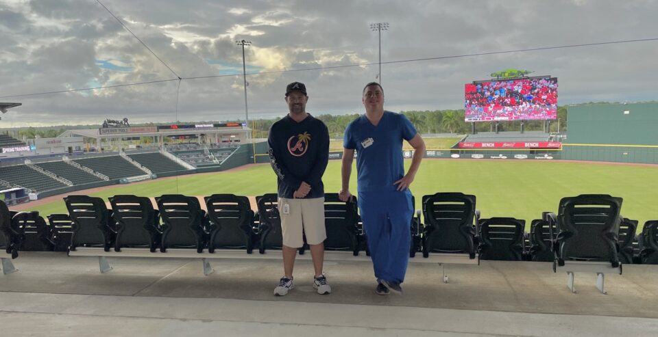 Two men standing in front of a baseball stadium. Two men standing in front of a baseball stadium.