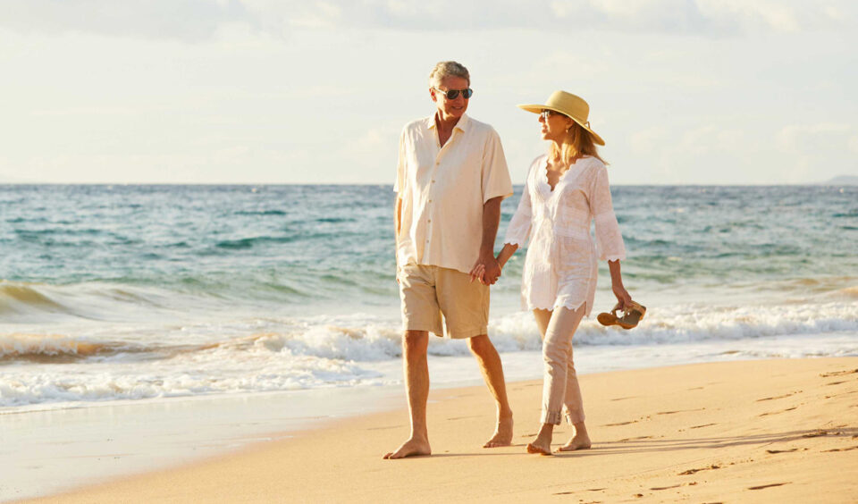 A man and woman holding hands on a beach.