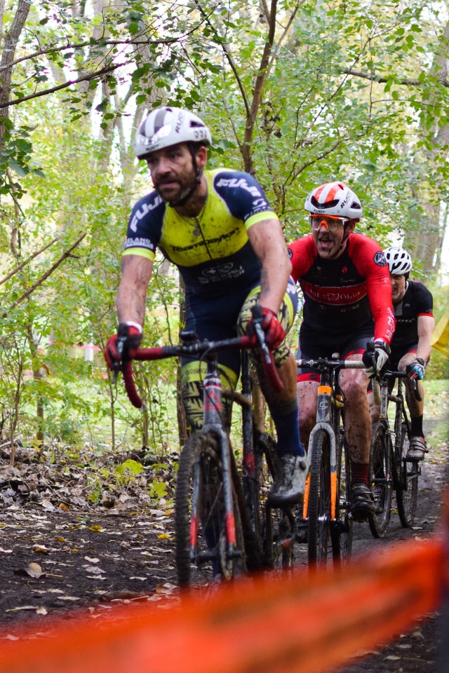 A group of cyclists riding down a trail in the woods.