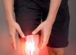 A man is holding his knee with a light on it.