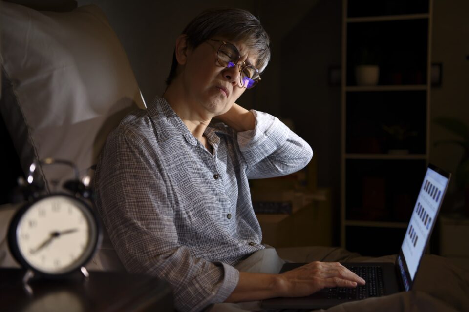 A woman sitting on a bed with a laptop.
