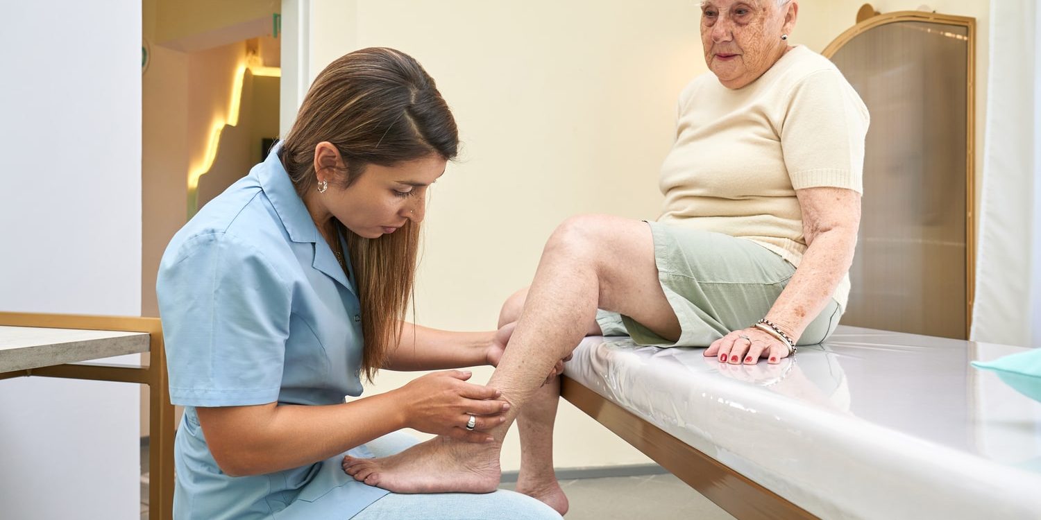 A nurse giving an elderly woman a foot massage. A nurse checking on an elderly woman