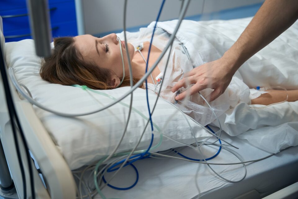A woman is lying in a hospital bed with an oxygen tube.