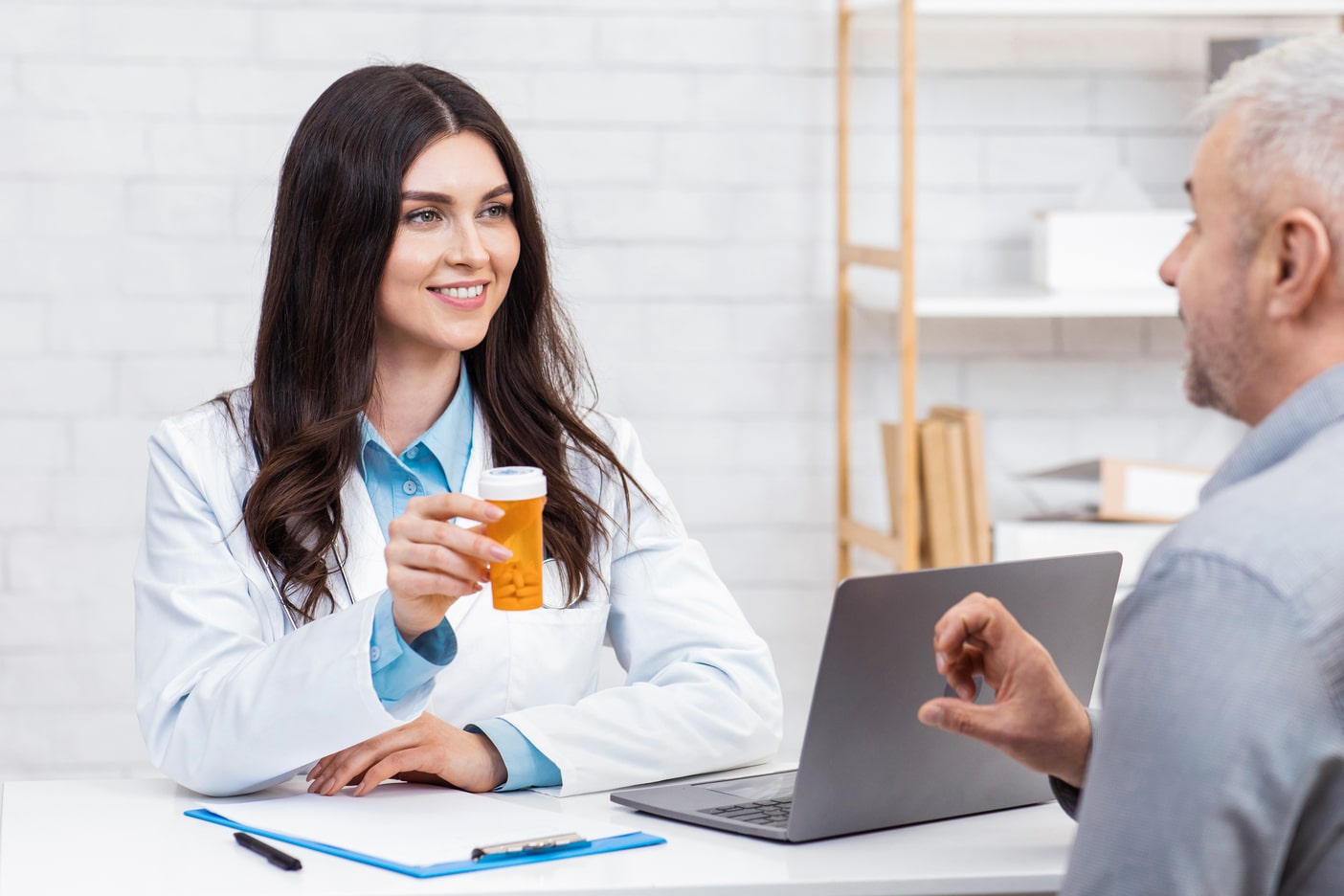 A doctor is talking to a patient in front of a laptop.