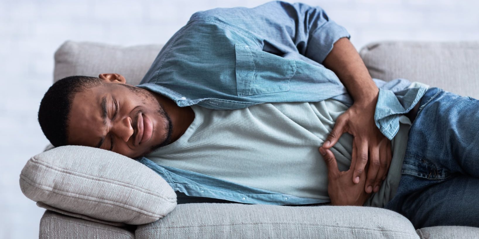 A man lying on a couch with a stomachache. A man lying on a couch with a stomachache.