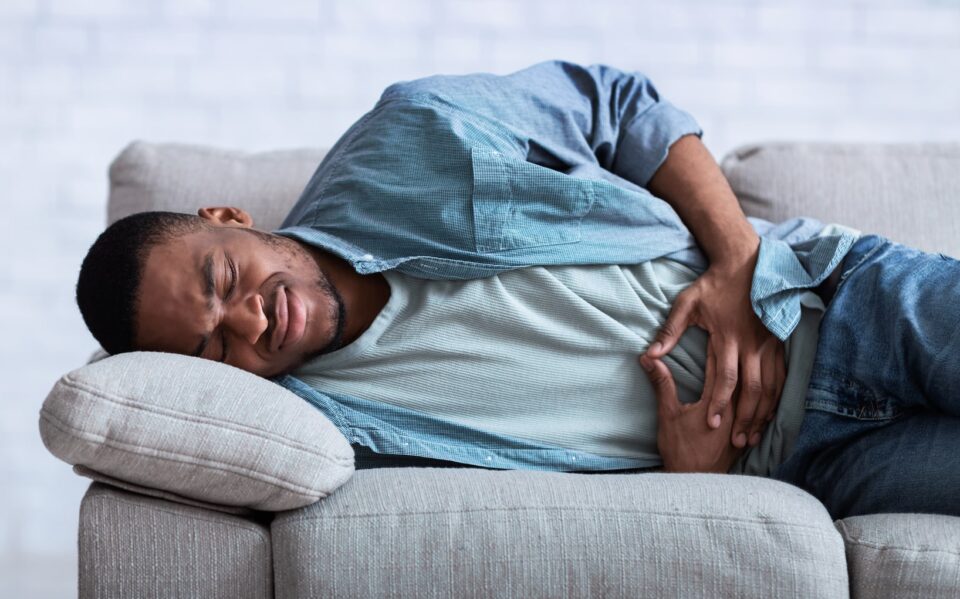 A man lying on a couch with a stomachache.