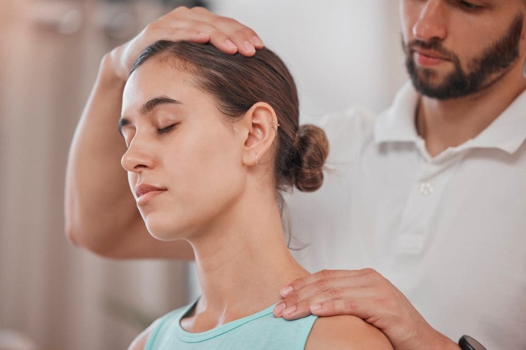 A woman having her neck massaged by a physiotherapist.