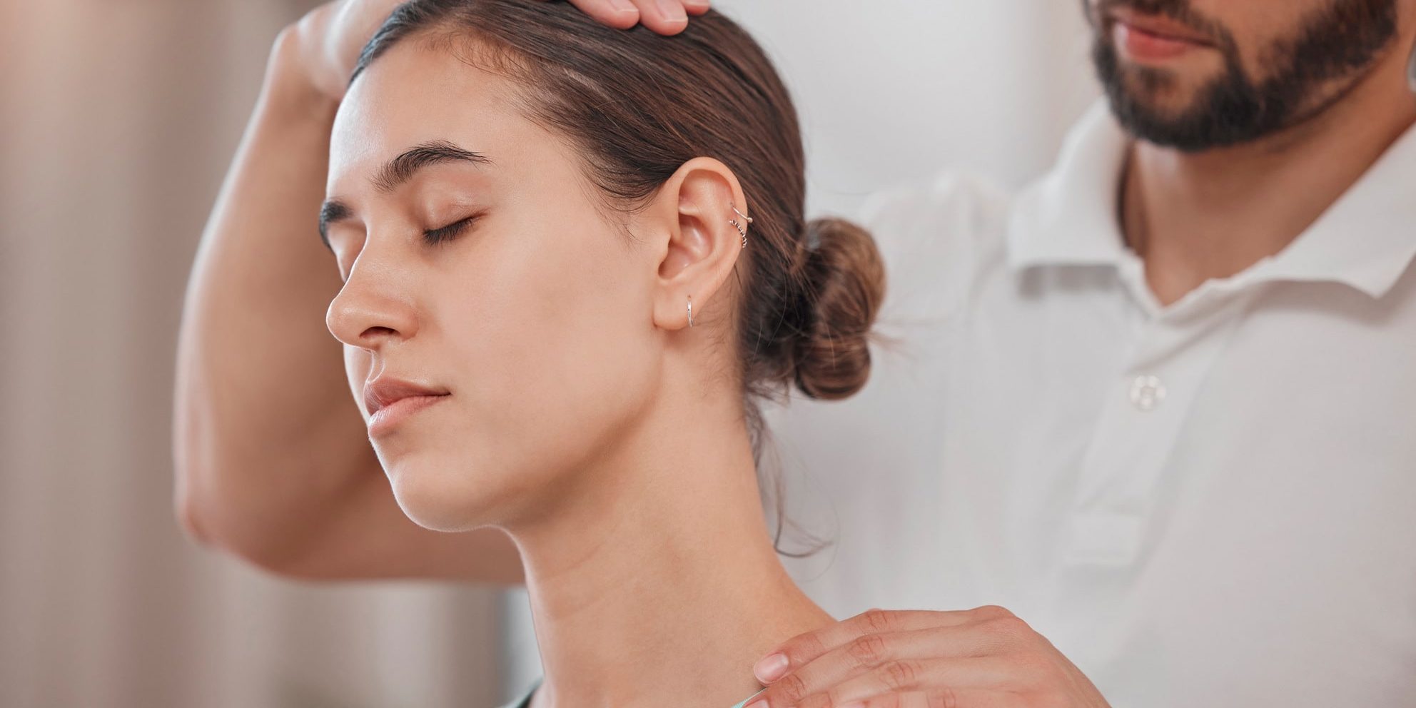 A woman having her neck massaged by a physiotherapist.