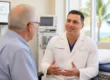 A doctor in a white coat talks to an older male patient in a medical office with palm trees visible outside the window. Discussing the use of Botox for Chronic Migraines.