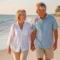 Active senior couple walking happily on a Venice, Florida beach, symbolizing mobility and relief from spinal stenosis pain via minuteman procedure.